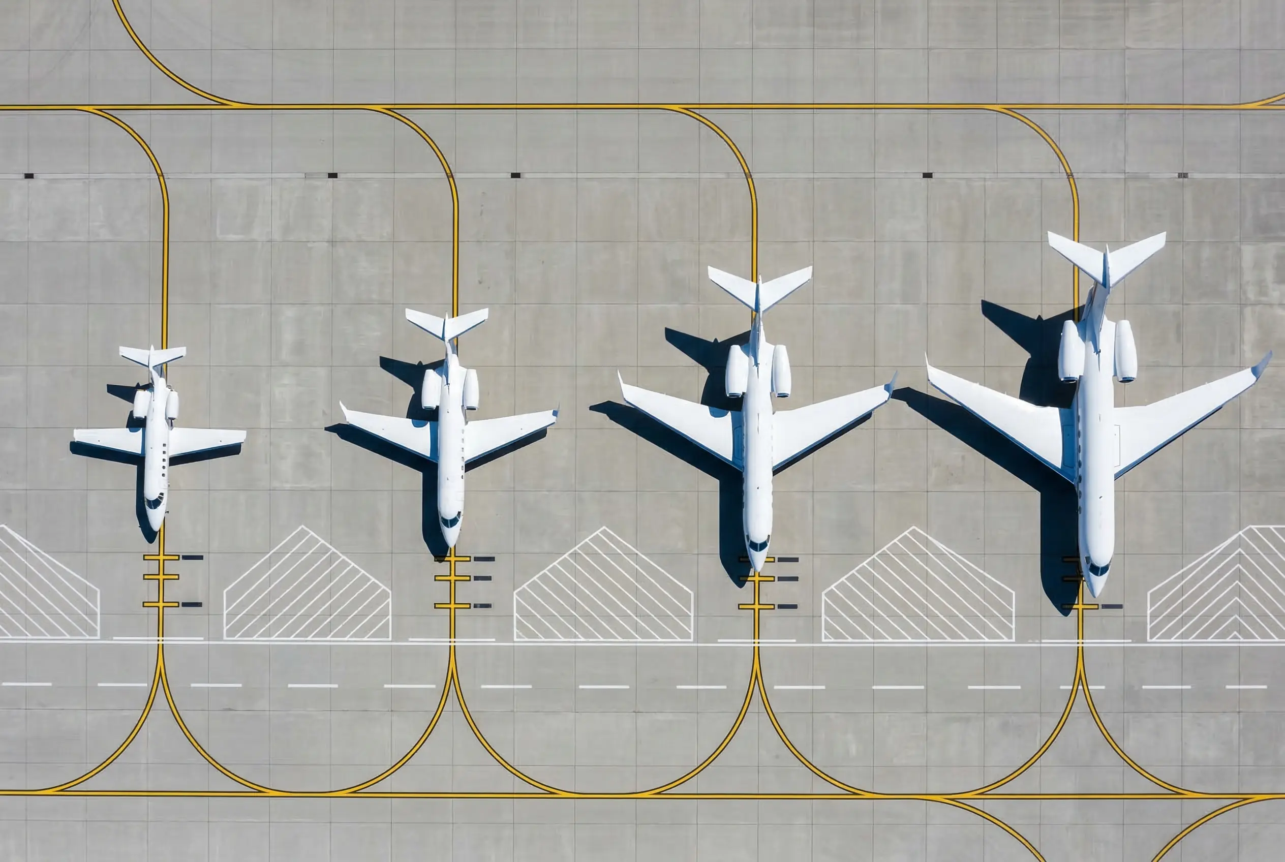 Four private jets of increasing size parked on an airport ramp